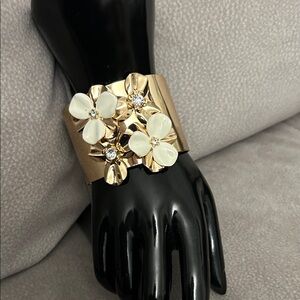 NWOT gold-tone cuff bracelet with white enamel flowers and rhinestone accents.